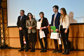 Pokaż zdjęcie: Pięć osób stoi na scenie i pozuje do zcjęcia